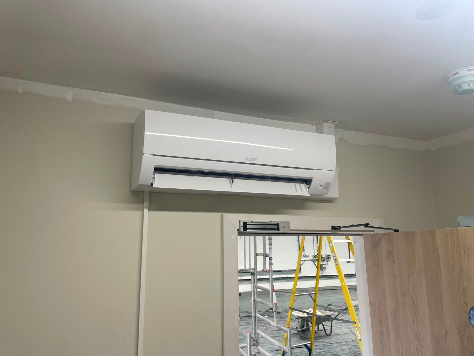 Outdoor heat pump condenser mounted on anti-vibration feet beside a North West property.