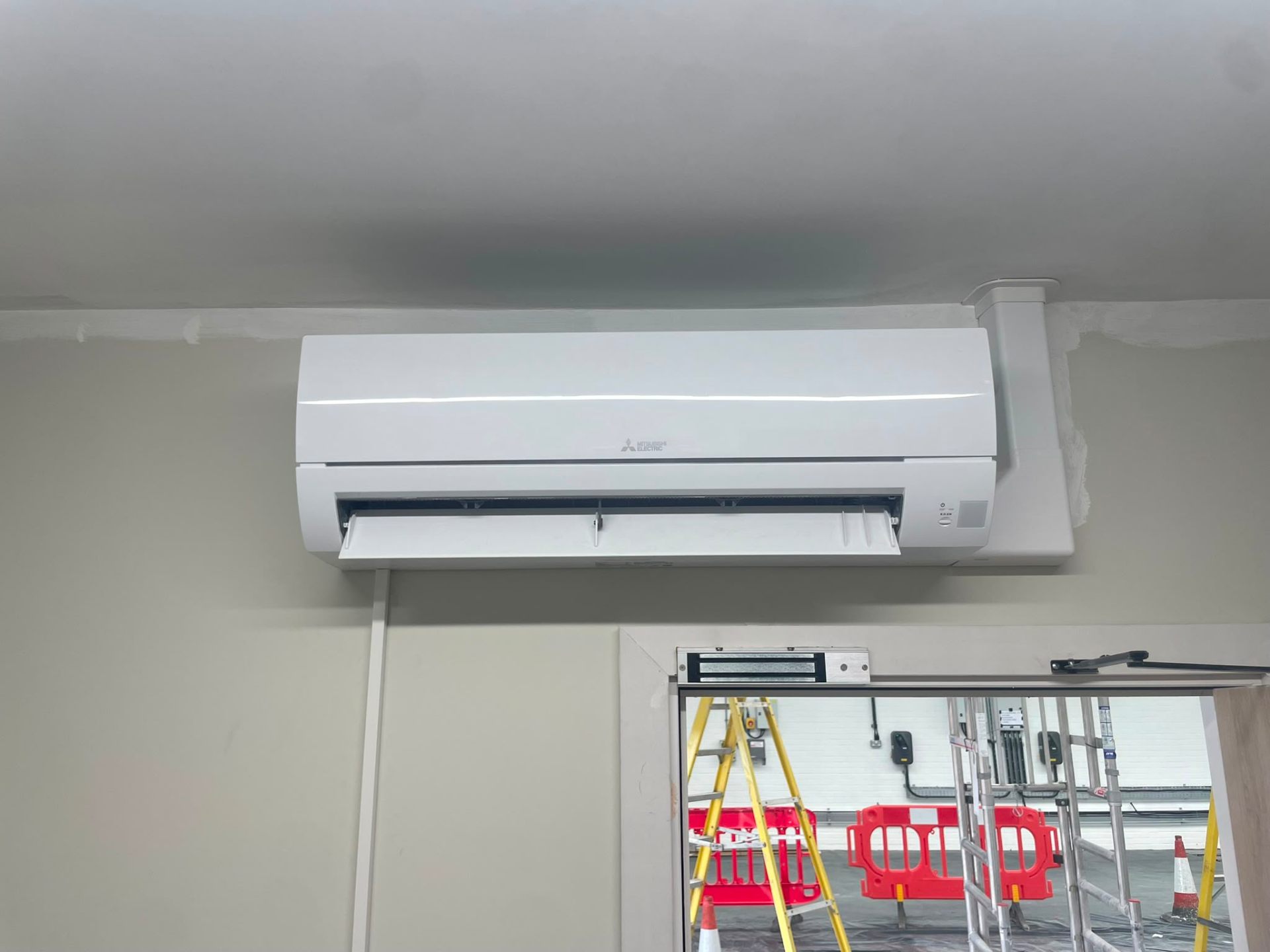 Outdoor air conditioning condenser unit installed on wall brackets with neat copper pipework, Manchester.