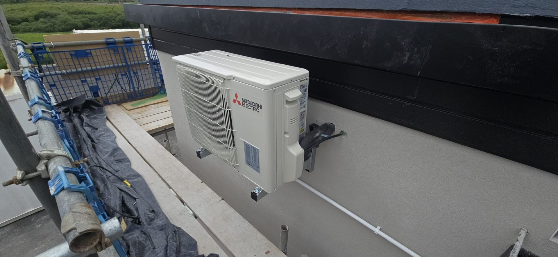 High-wall Mitsubishi air conditioning unit installed in a residential bedroom in Greater Manchester.